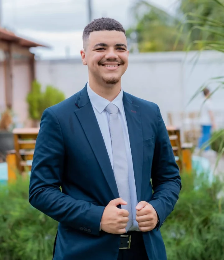 João Pedro Viana, de terno azul, sorrindo num jardim